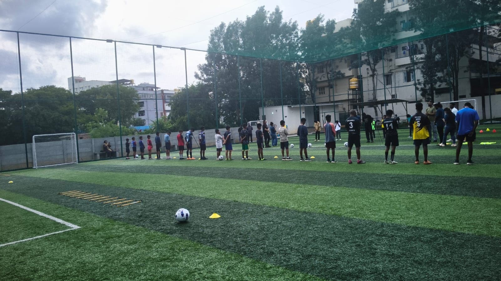 A long line of children spread across a green football pitch during a training drill.